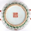 Een ronde Chinese dekselpot van meerkleurig porselein met een decor van draken en een vlammende parel. Onderaan met Qianlong-merk.