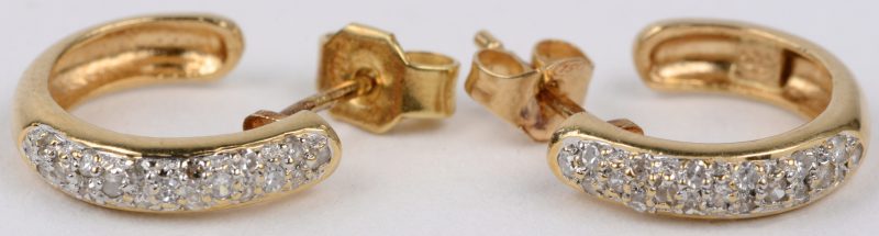 Een paar 18 karaats wit en geel gouden oorbellen bezet met briljanten met een gezamenlijk gewicht van ± 0,40 ct.