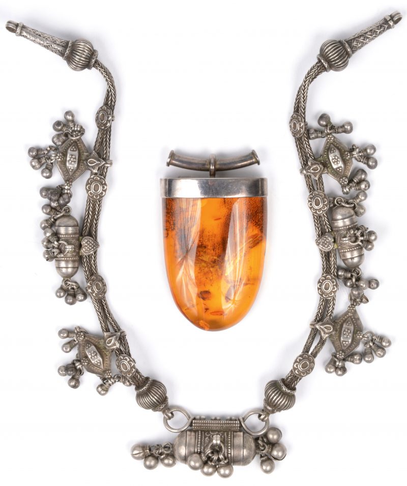 Een zilveren halssnoer en een hanger van zilver en met amber.