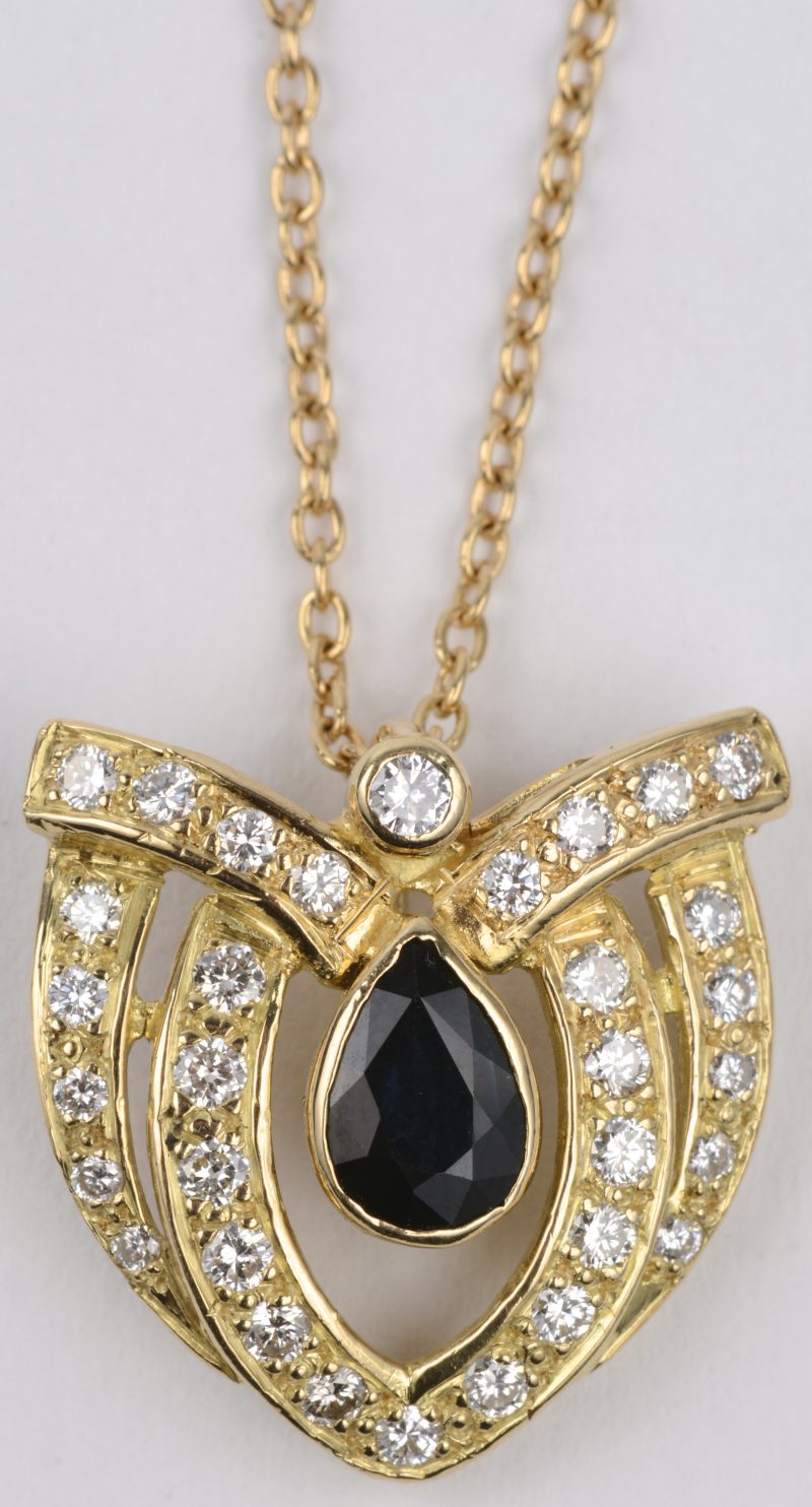 Een 18 karaats geel gouden ketting met hanger bezet met diamanten met een gezamenlijk gewicht van ± 0,60 ct. en een druppelvormige saffier van ± 1,50 ct.