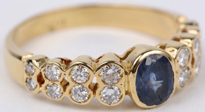 Een 18 karaats geel gouden ring bezet met diamanten met een gezamenlijk gewicht van ± 0,40 ct. en een centrale saffier van ± 0,50 ct.
