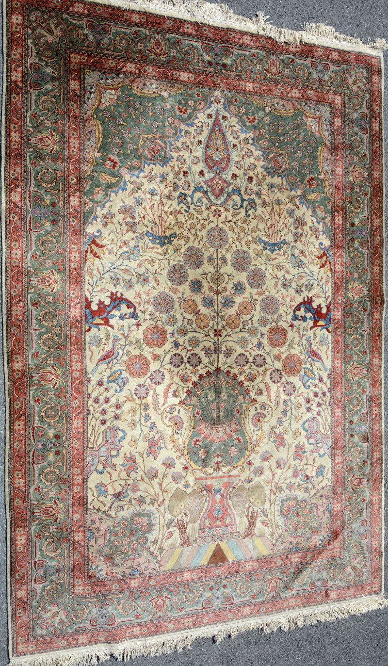 Een handgeknoopt Perzisch wollen tapijt met een decor van bloemen en vogels.