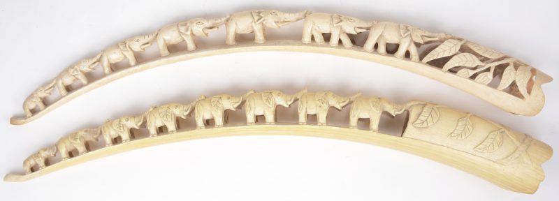 Twee gesculpteerde Afrikaanse slagtanden in de vorm van een dubbele rij olifantjes.