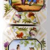 Twee rechthoekige theeflessen van meerkleurig en verguld Frans porselein, versierd met een decor van landschappen, bloemen en personages. In een gefineerd palissanderhouten doosje met sleuteltje. Eind XIXe eeuw.