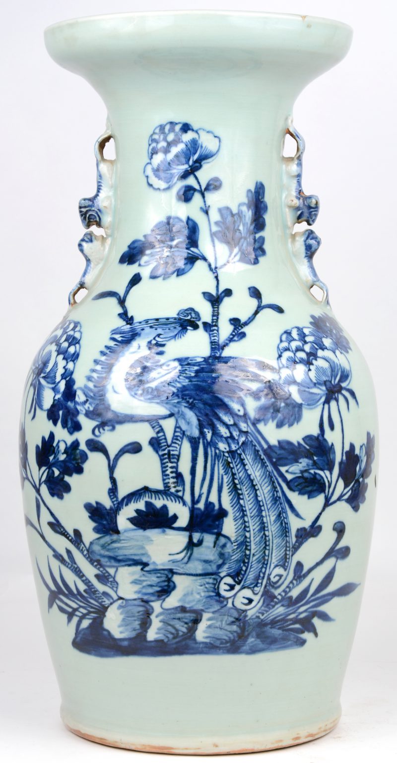 Een balustervaas van Chinees porselein met een blauw en wit decor van een pauw en pioenrozen. De hals versierd met leeuwtjes in hoogreliëf.