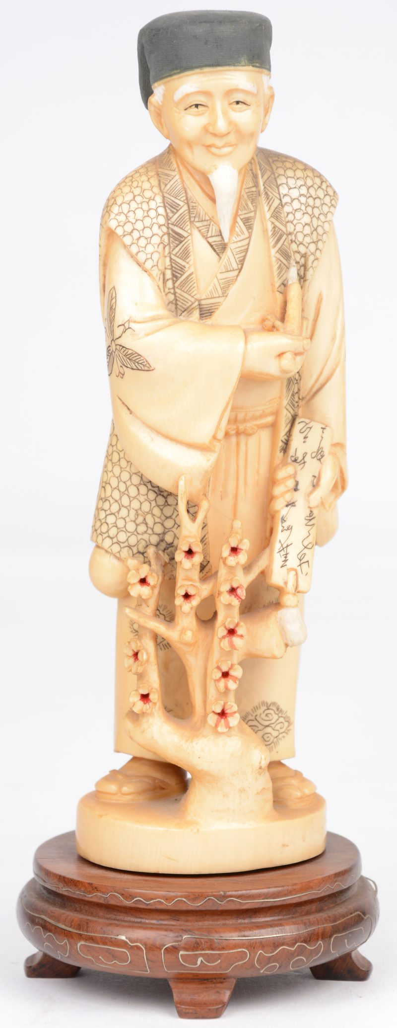“Kaligraaf”. Een beeldje van gesculpteerd en deels gepolychromeerd ivoor op een houten voetstukje.