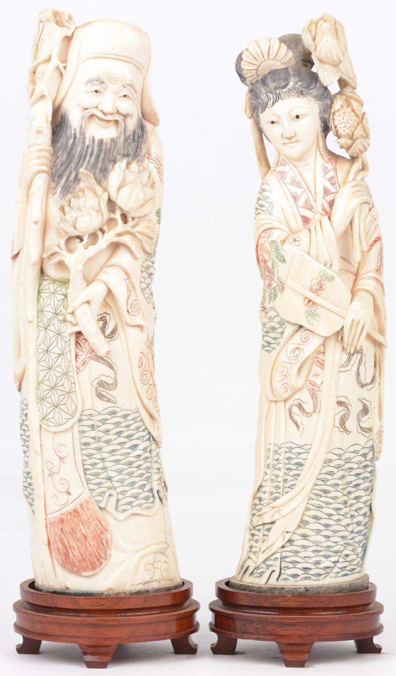 “Man en vrouw met bloemen”. Een paar beeldjes van gesculpteerd en deels gepolychromeerd ivoor op houten voetstukjes.