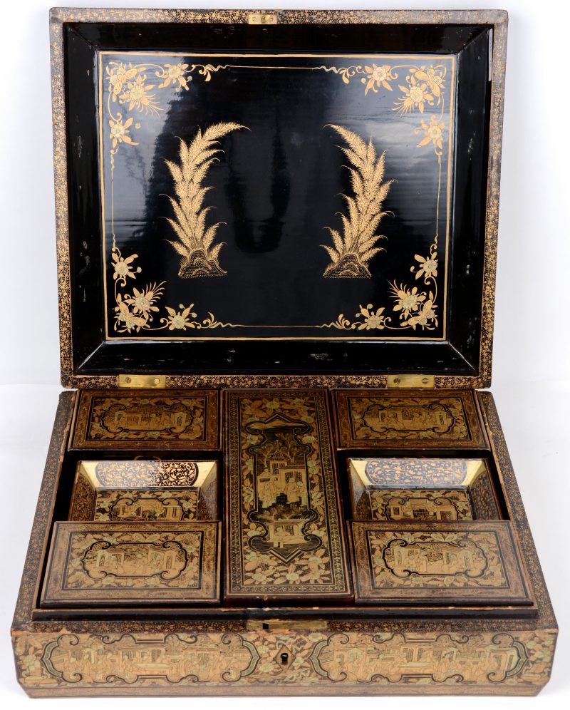 Een Chinese doos van zwartgelakt hout met een verguld decor met paleisscènes. Binnenin vijf dekseldoosjes en twaalf rechthoekige schaaltjes, evenals een groot aantal ivoren speelchips in zes maten. Zonder sleuteltje.