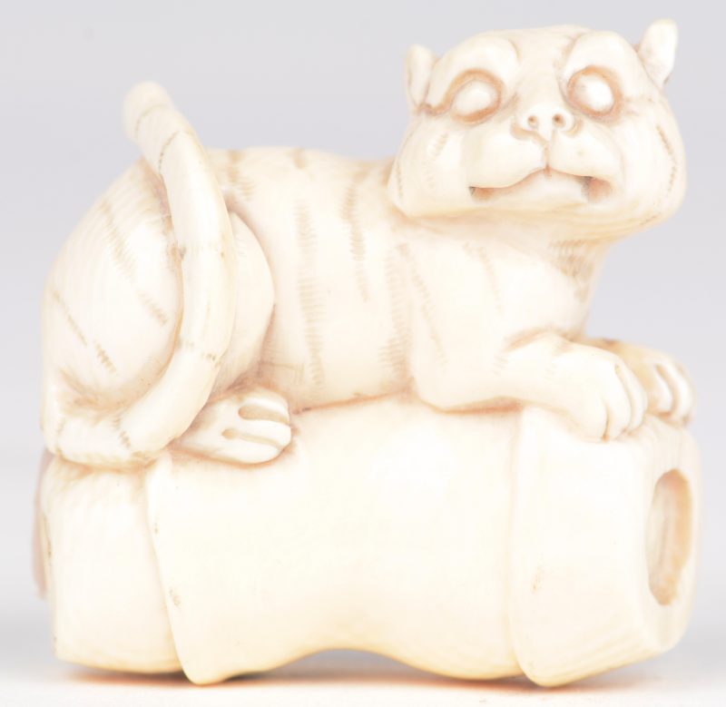 “Tijgerkat op een kussen”. Netsuké van gebeeldhouwd ivoor. Japan, eerste kwart XXste eeuw. Onderaan gemerkt.