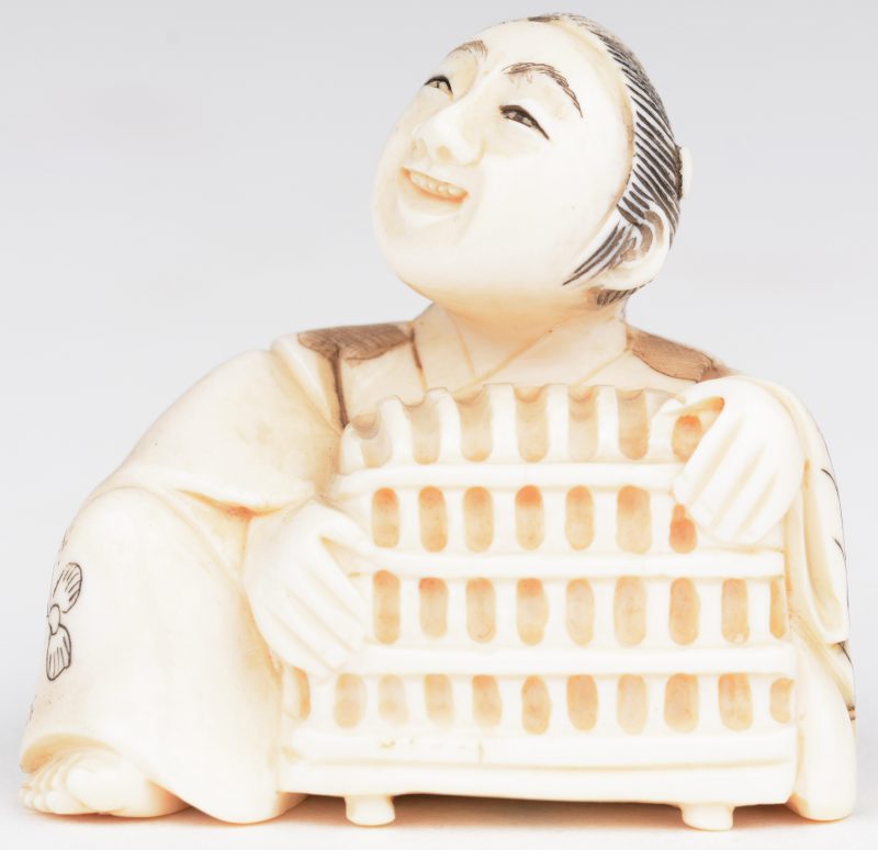 “Man met kevie”. Netsuké van gebeeldhouwd ivoor. Japan, eerste kwart XXste eeuw. Onderaan gemerkt.