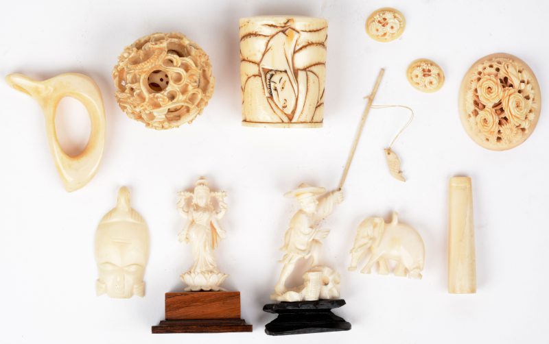 Een lot bestaande uit een handvat voor een wandelstok (Japan, omstreeks 1900), een concentrische bol (China, eerste helft XXste eeuw), een beeldje van een visser, een Bodhisatva, een bloemstukje en enkele andere voorwerpen van bewerkt en gebeeldhouwd ivoor.