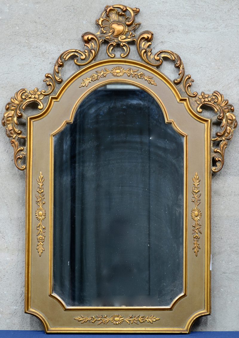 Een spiegel van verguld hout in barokke stijl met een rocaille in de kuif.