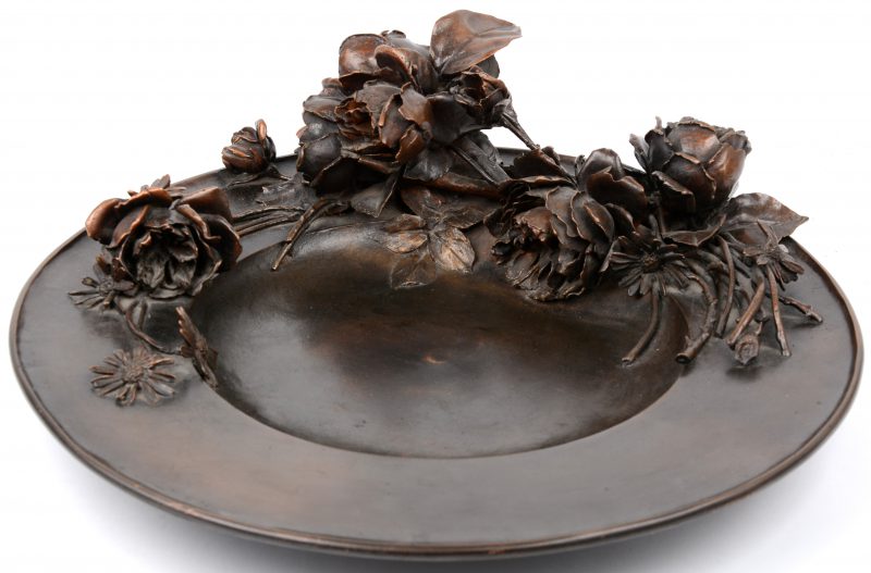 Een bronzen sierschotel, versierd met bloemen in hoogreliëf.
