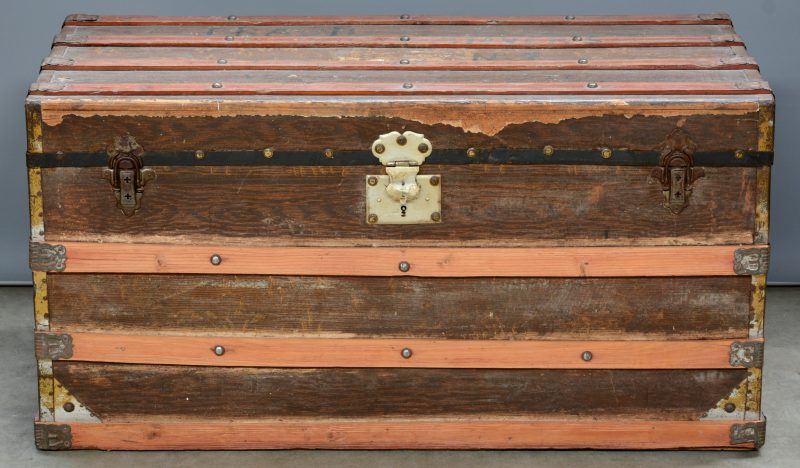 Een oude houten reiskoffer met messingen monturen.