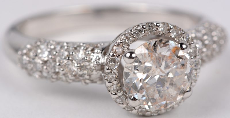 Een 18 karaats wit gouden ring bezet met diamanten met een gezamenlijk gewicht van ± 0,60 ct. en een centrale diamant van ± 1,05 ct.