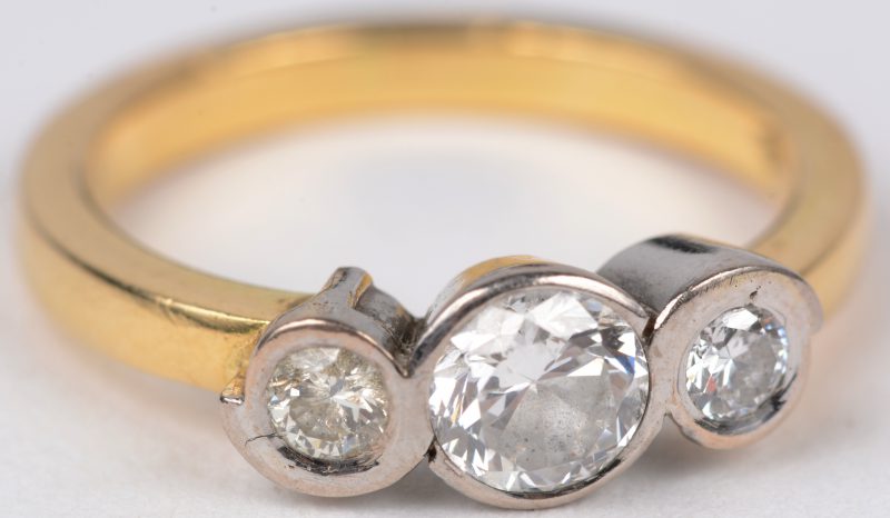 Een 18 karaats wit en geel gouden ring bezet met drie diamanten met een gezamenlijk gewicht van ± 0,70 ct.