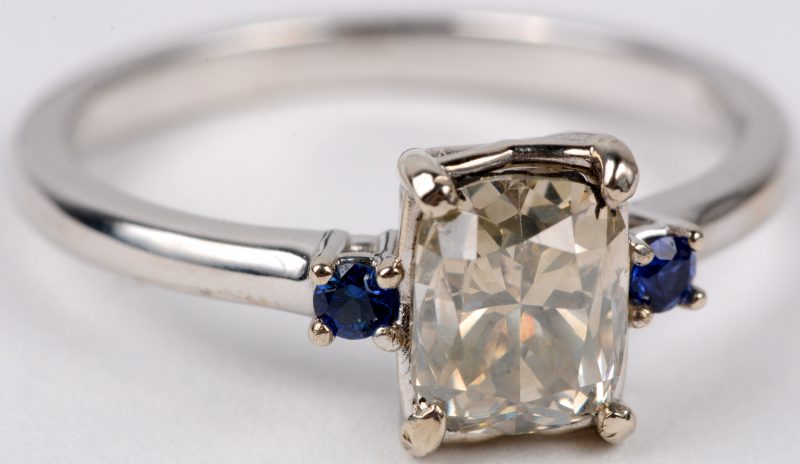 Een 14 karaats wit gouden ring bezet met een centrale natural diamant van ± 1,36 ct. SI1. en twee saffiertjes.
