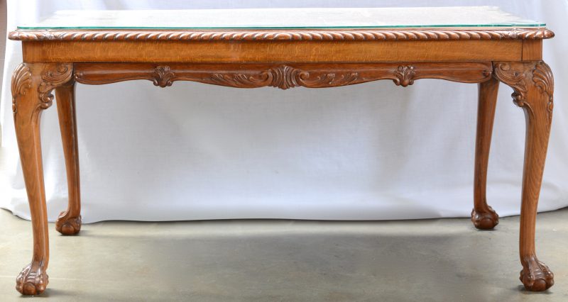 Een houten salontafel in Chippendalestijl met een glazen blad.