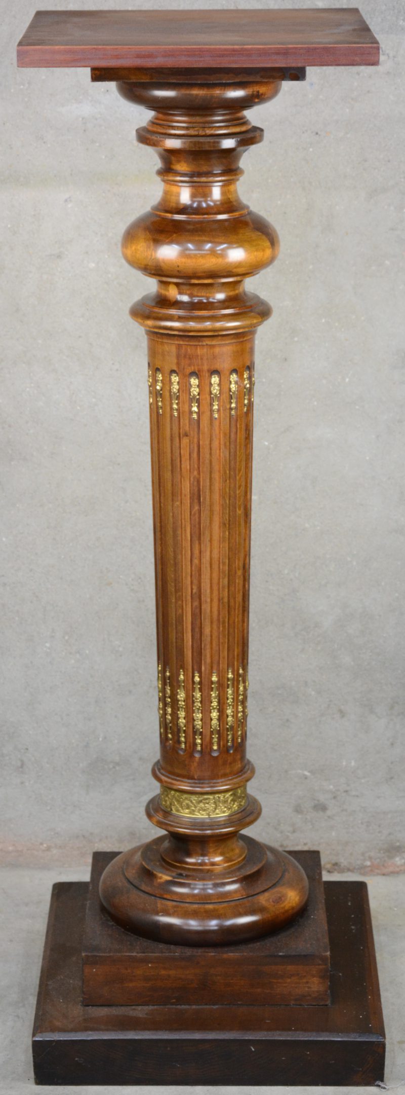 Een zuilvormige piedestal van gebeeldhouwd en gedraaid hout, versierd met messingen monturen.