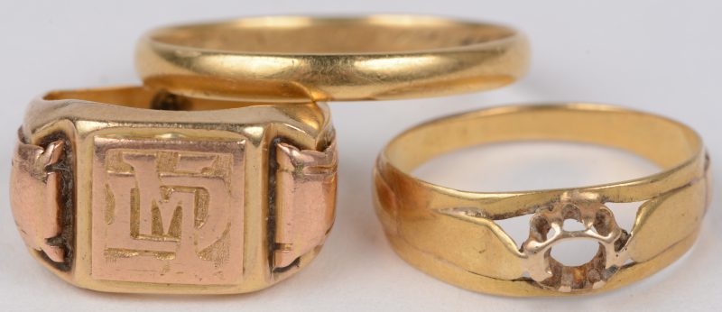Een cachetring met initialen een trouwring en een ring zonder steen van 18 karaats geel goud.
