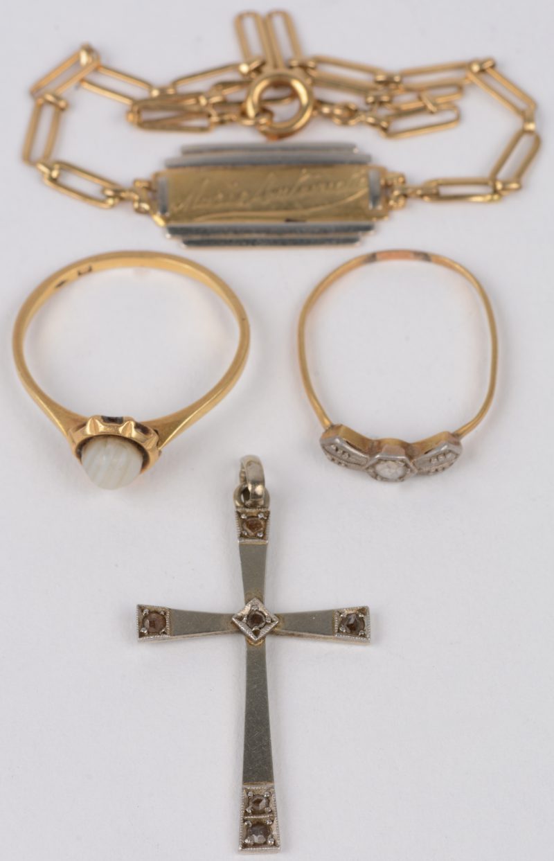 Een 18 karaats wit gouden kruisje bezet met diamantjes oude slijp. We voegen er een armbandje en twee verschillende ringen van 18 karaats wit en geel goud aan toe.