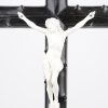 Een kruisbeeld van zwartgepatineerd hout met een witgepatineerde metalen corpus. Op los voetstuk.