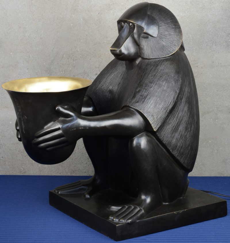Een lamp van donkergepatineerd brons in de vorm van een baviaan met een vaas in art decostijl.