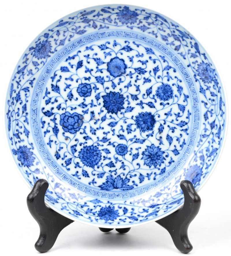 Een schoteltje van Chinees porselein met een blauw en wit decor van bloemen. Onderaan gemerkt.