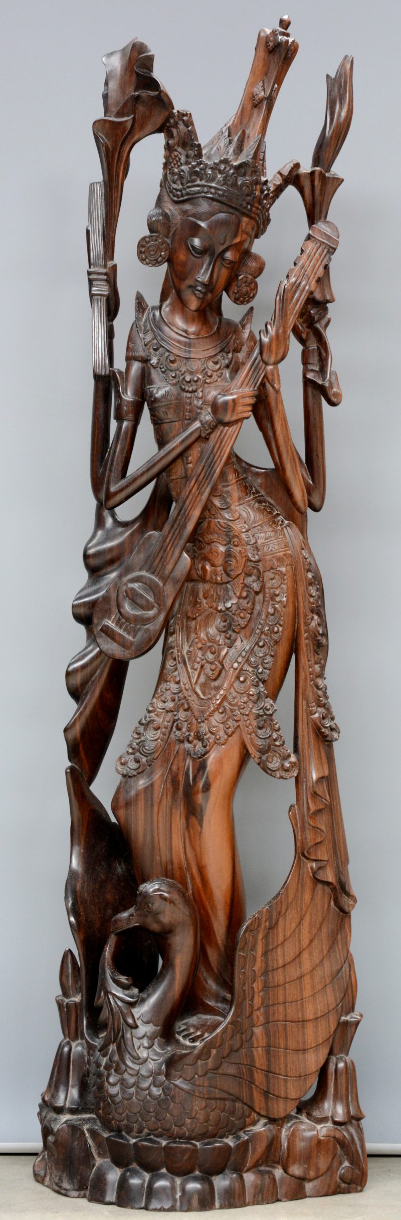 Een beeld van een musicerende godheid op een zwaan van gebeeldhouwd hardhout. Zuid-Oost-Azië.
