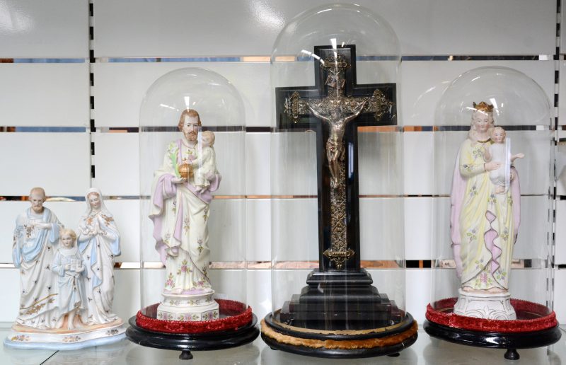 Drie glazen stolpen met houten voetstuk met drie Heiligenbeelden van meerkleurig biscuit en een kruisbeeld van verzilverd koper en zwartgelakt hout.