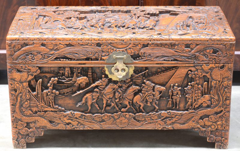 Een Chinese houten kist, versierd met gebeeldhouwde scènes van ruiters in de panelen.