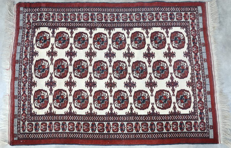 Een antiek handgeknoopt Oosters karpetje van wol met een Bocharamotief. Slijtage.