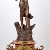 Een driedelig art nouveau klokstel van rood marmer en zamak. De pendule getooid met een beeld, getiteld ‘Coquette’. De twee kandelaars met vier armen. Begin XXe eeuw.