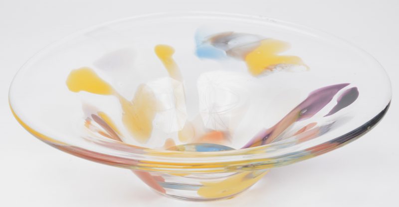 Een schaal van geblazen glas met gekleurde vlekken. Onderaan gemerkt ‘HR’.