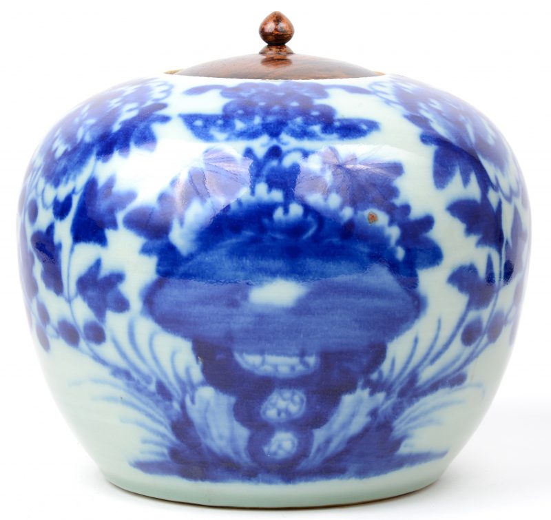 Een gemberpot van Chinees porselein met een houten deksel en een blauw en wit decor van pioenen.