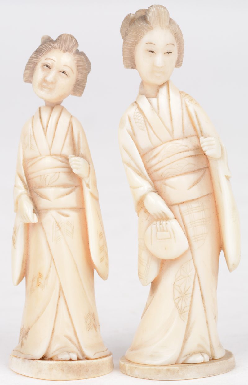 Twee kleine geisha’s van gebeeldhouwd ivoor. Japans werk, begin XXste eeuw. Onderaan gesigneerd.