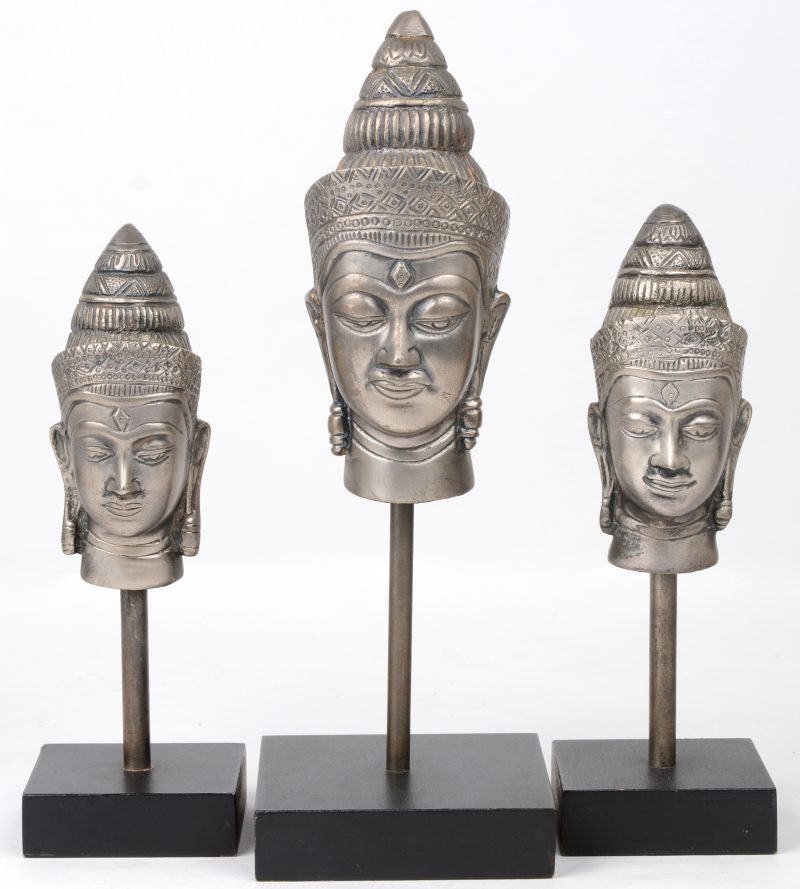 Een reeks van drie metalen Boeddhahoofden in oplopende groottes.