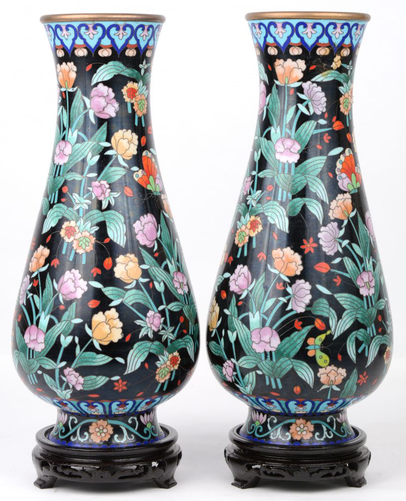 Een paar vazen van cloisonné op koper met een decor van vlinders en bloemen. Met houten sokkels.