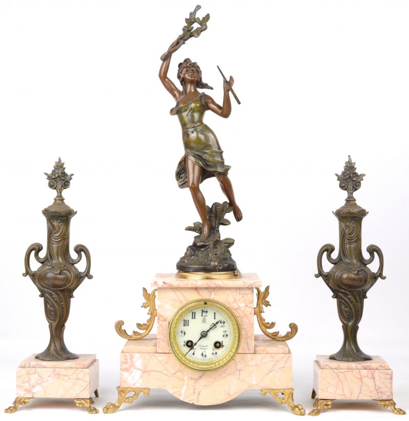 Klokstel van marmer en zamak. Twee cassoletten en een pendule versierd met een allegorische figuur.