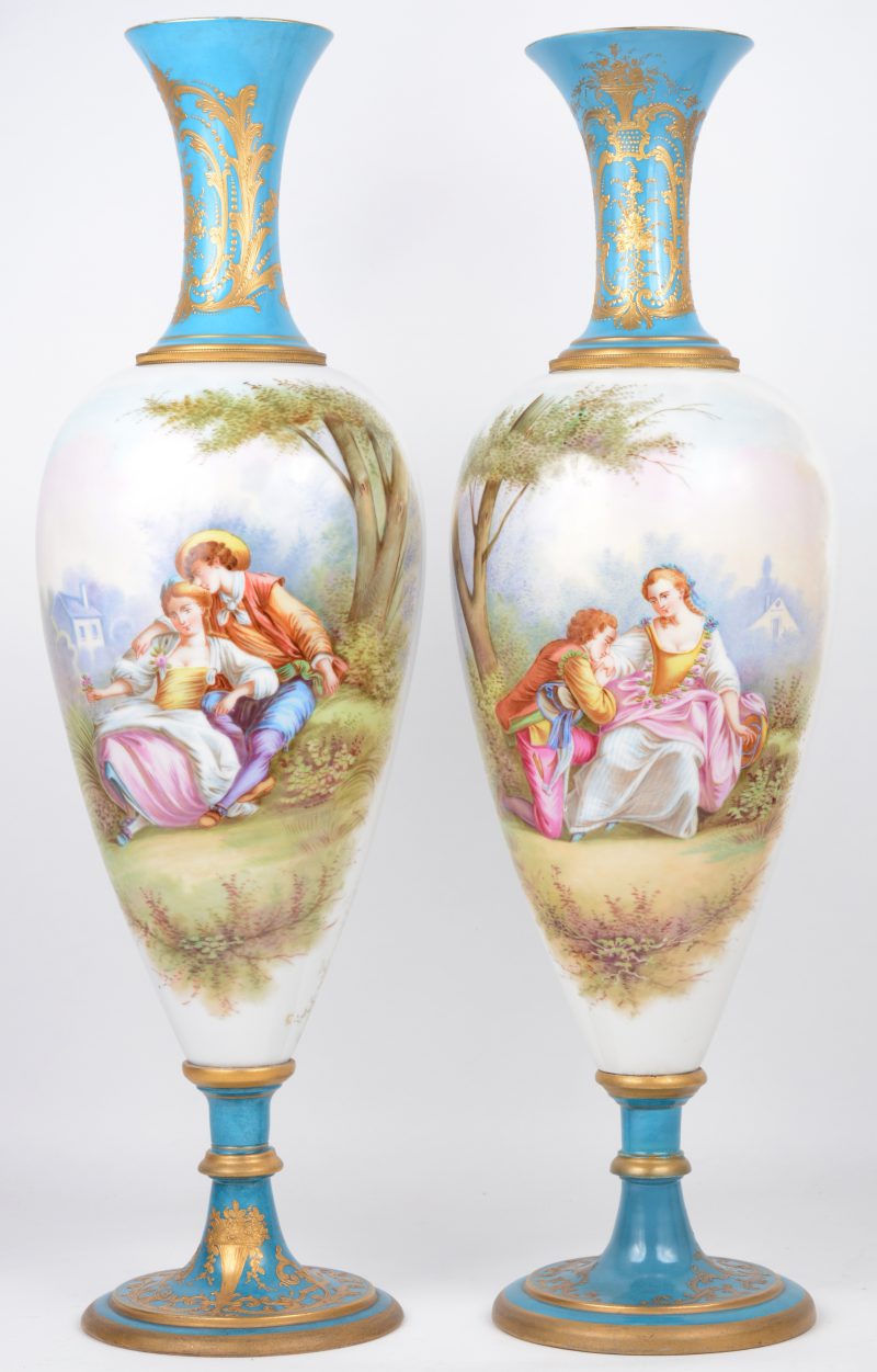 Een paar vazen van meerkleurig porselein, versierd met handgeschilderde decors van romantische koppels in een landschap. De voet en en de hals versierd met vergulde motieven op blauwe fond.  Onderaan gemerkt.