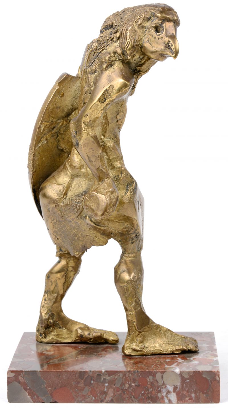 “Mensenfiguur met vogelkop”. Een bronzen beeldje op rood marmeren sokkel.