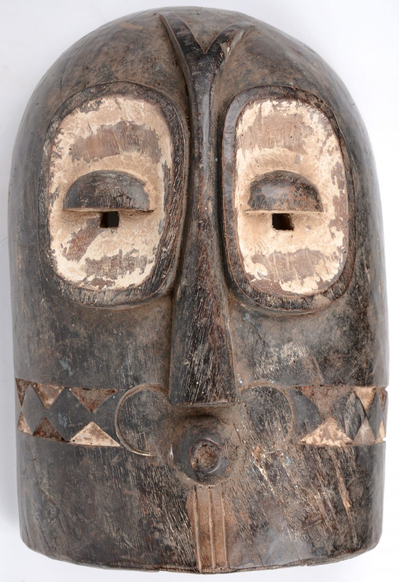 Een masker van gebeeldhouwd hout met witgepatineerde details. Dembe, D.R. Congo.