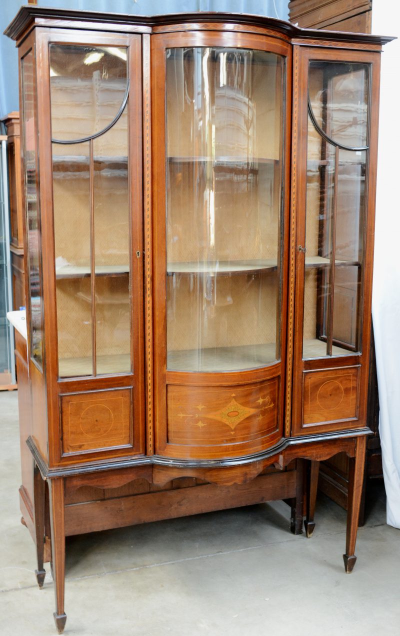 Een Engelse vitrine van gefineerd hout met twee deuren naast een centraal gebogen glas.