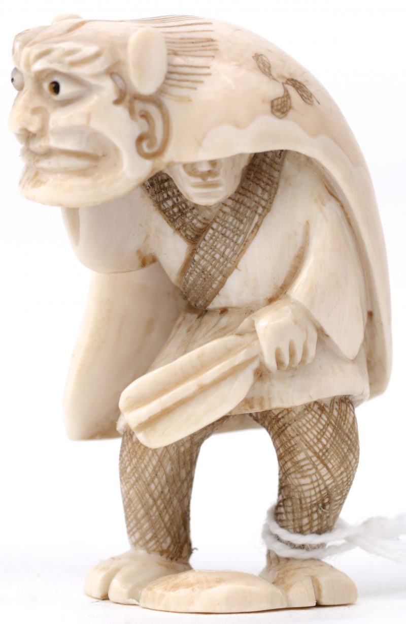 “Verklede man”. Een netsuke van gesculpteerd ivoor. Onderaan gesigneerd. Eerste kwart XXe eeuw.