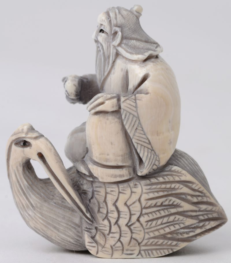 “Wijze op pelikaan”. Een netsuke van gesculpteerd ivoor. Achteraan gesigneerd. Eerste kwart XXe eeuw.
