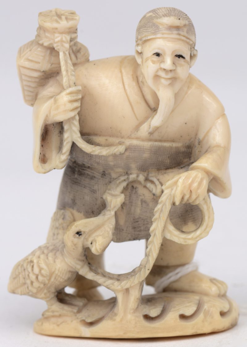 “Reiziger met vogel”. Een netsuke van gesculpteerd ivoor. Gesigneerd. Eerste kwart XXe eeuw.