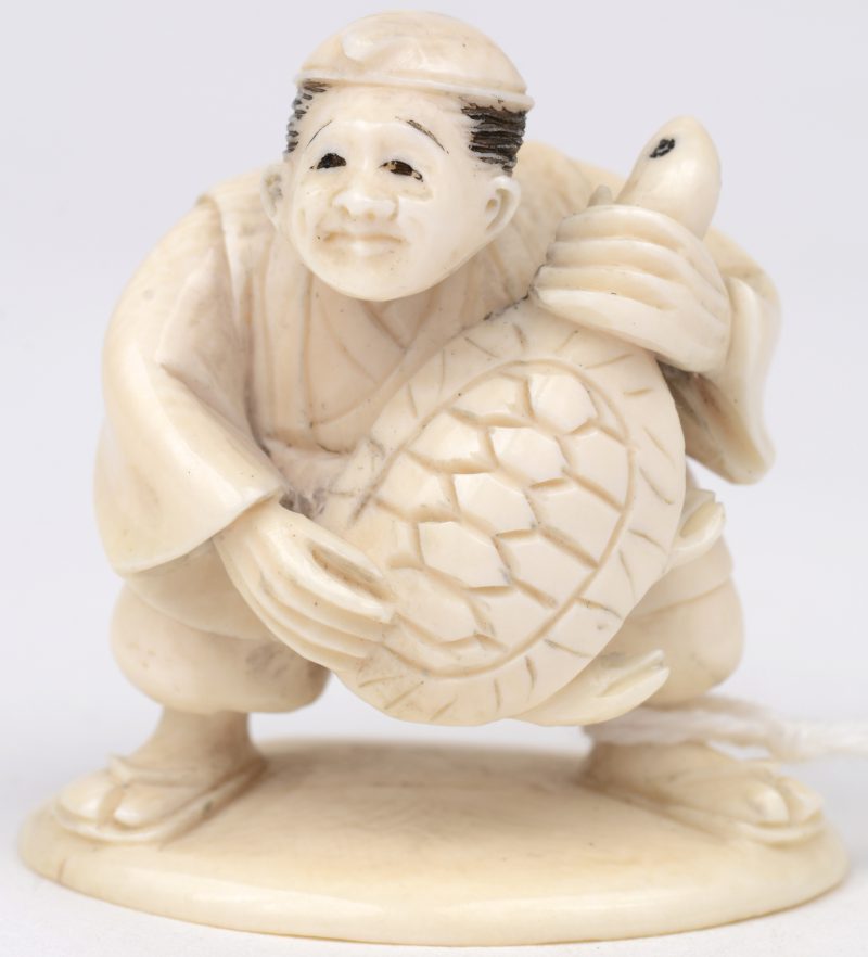 “Man met schildpad”. een Japanse gordelknoop van gesculpteerd ivoor. Onderaan gesigneerd. Eerste kwart XXe eeuw.