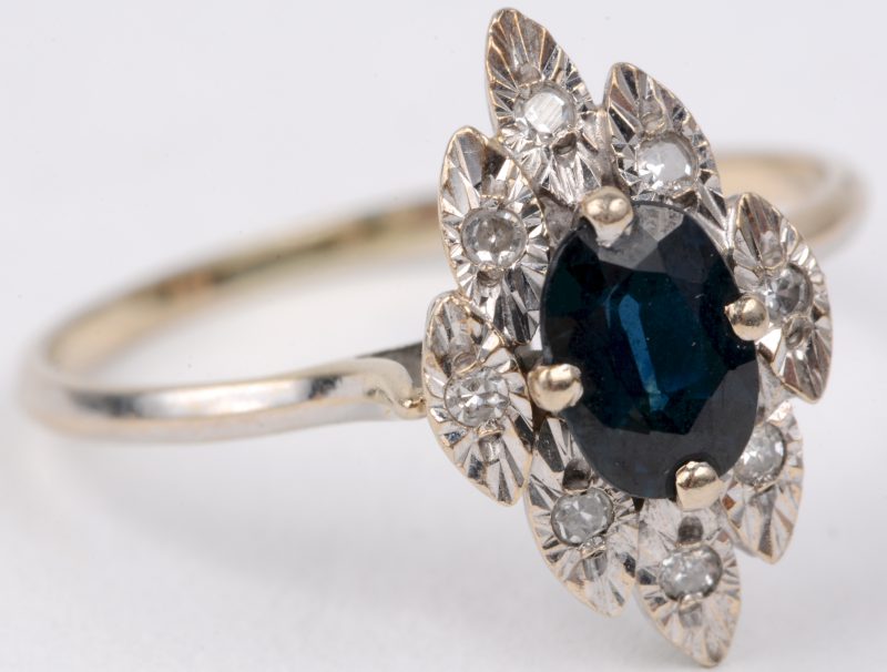 Een 18 karaats wit gouden ring bezet met acht kleine diamantjes oude slijp en een centrale saffier van ± 0,30 ct.
