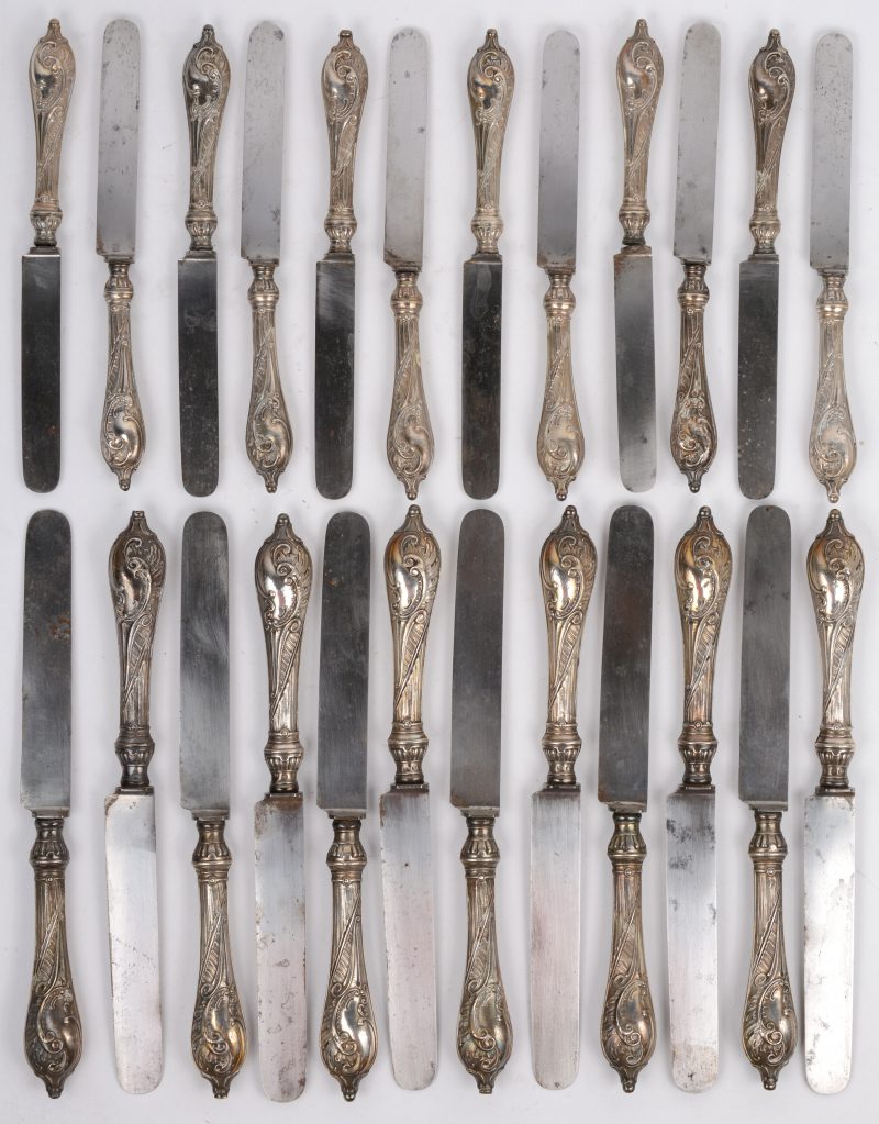Serie van 12 grote en 12 kleine messen met gedreven en geciseleerde zilveren rocailleheften. Duitse keuren, einde XIXde eeuw en 800 ‰. Originele stalen bladen.