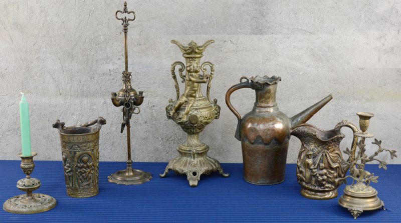 Een gevarieerd lot koper, messing en brons, bestaande uit een olielamp, kandelaars, een wijwatervat en twee kruiken.